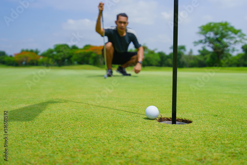 Golfer putt golf ball into hole on the green at golf course