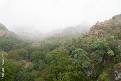 Fog view on the Khndzoresk ancient cave city in the mountain rocks. Armenia landscape attraction. Abandoned ruins in the mist. Atmospheric stock photography.