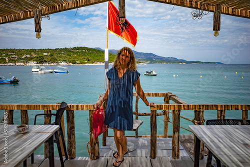 Ksamil, Albania,  A Scandinavian tourist stads under a thatched roof at the beach. photo