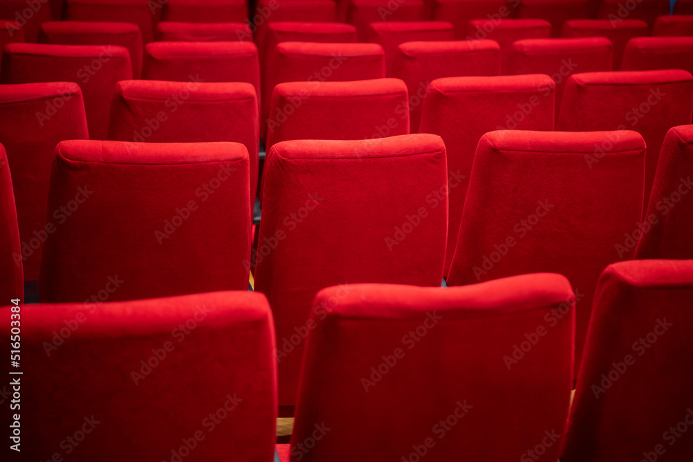 Cinema movie theater background. Red cozy cinema seats in empty theater. Armchairs with comfortable elbows.