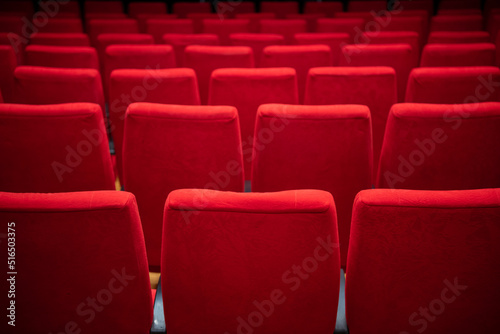 Cinema movie theater background. Red cozy cinema seats in empty theater. Armchairs with comfortable elbows.