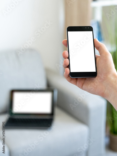 Online message. Digital mockup. Mobile communication. Unrecognizable man holding smartphone with blank screen in hands light room interior blur.