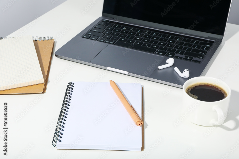 Workplace with laptop and blank notebook on white table Workplace with laptop and blank notebook on white table