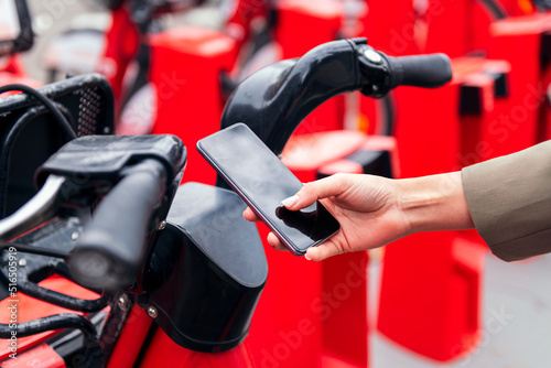 close up of a hand with a smart phone scanning the code to unlock the bike from the rental station, technology and sustainable mobility concept