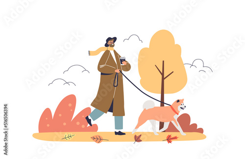 Man walking dog in autumn park. Young hipster guy in trendy trench drink coffee to go in fall forest