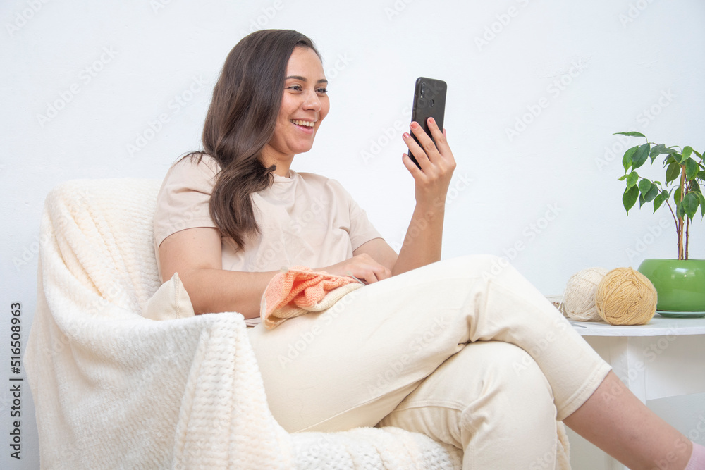 Woman sitting against a white wall talking on video chat Woman sitting against a white wall talking on video chat