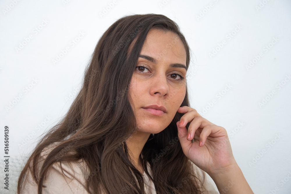 The girl sits on the background of a white wall looks into the frame The girl sits on the background of a white wall looks into the frame