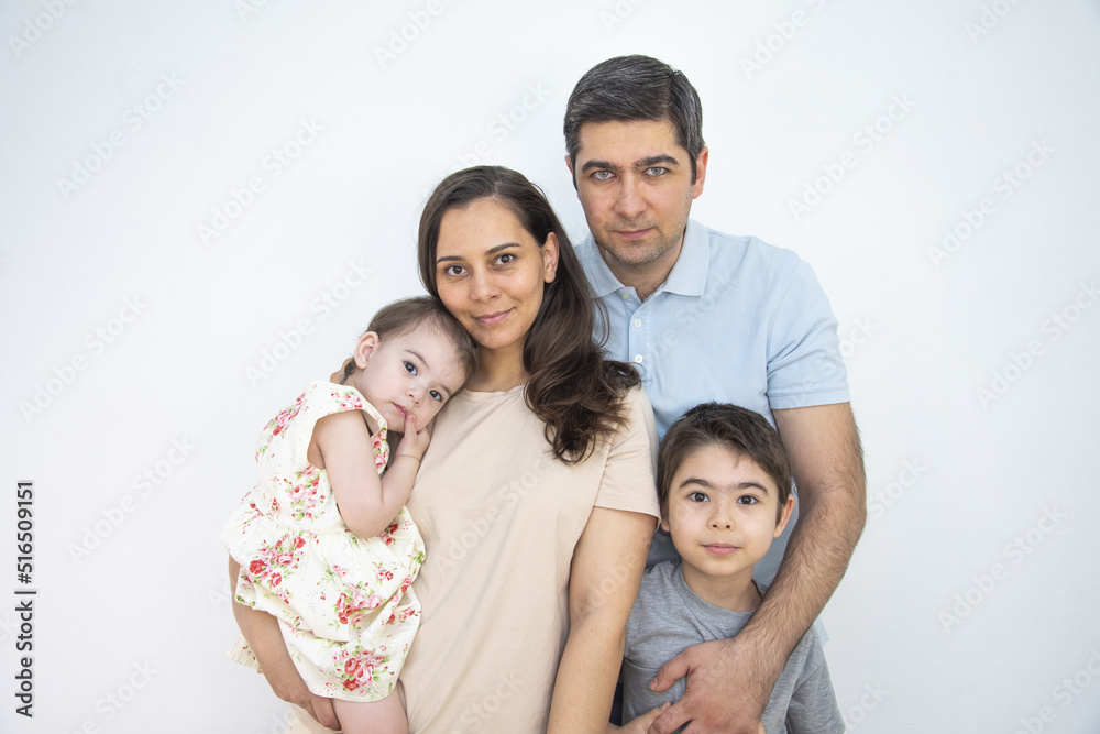 Family Mom Dad Daughter and Son standing near a white wall