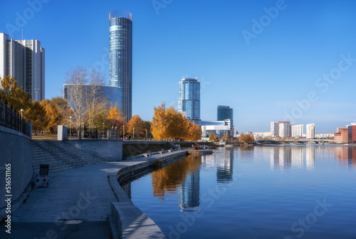 Embankment of the Iset River in Yekaterinburg (Russia) with a symmetrical reflection of high-rise buildings in the water. photo
