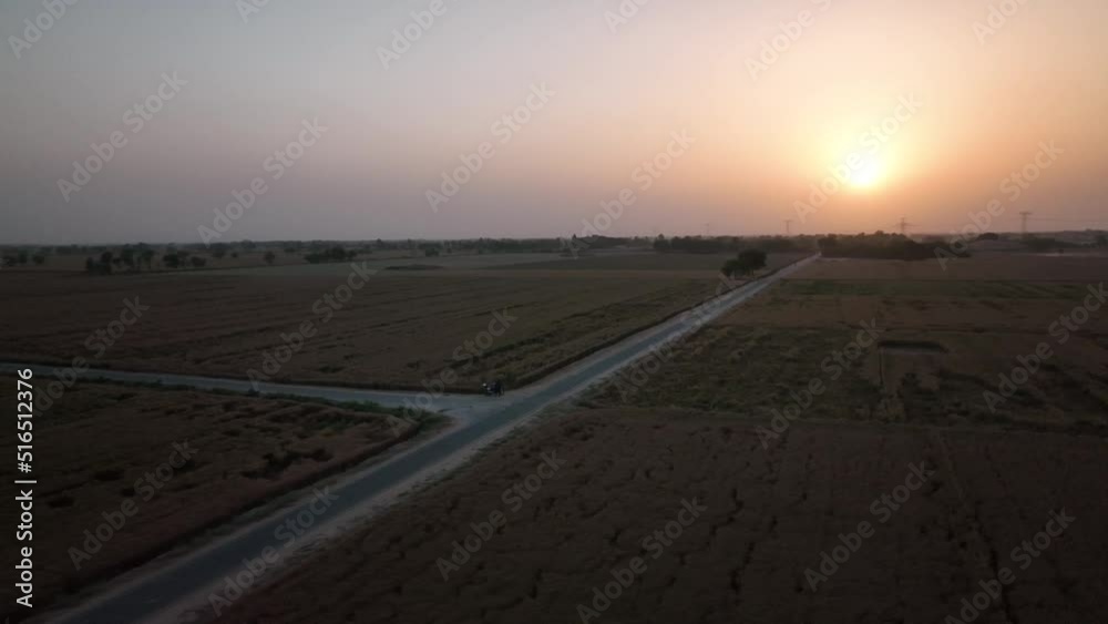 Aerial View Along Empty Road Through Rural Farm Land Against Orange Sunset Skies. Circle Dolly Aerial View Along Empty Road Through Rural Farm Land Against Orange Sunset Skies. Circle Dolly