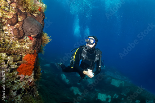 A female scuba diver explores a colourful reef in the deep blue of the Aegean Sea in Greece