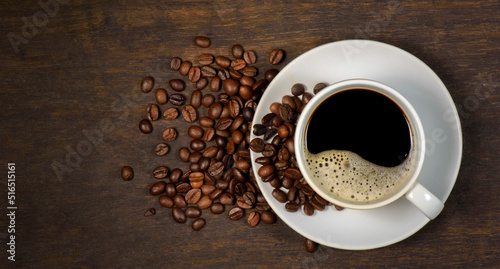 top view of hot coffee cup and coffee beans on wood background