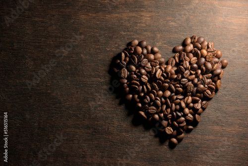 top view of heart shape coffee beans on wood background
