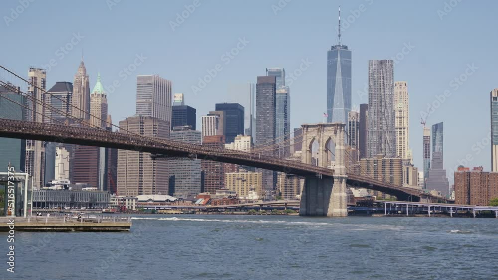 Manhattan's financial district with the One World Trade Center and the Brooklyn Bridge at a sunny day, static shot from the bankside of the East River. Manhattan's financial district with the One World Trade Center and the Brooklyn Bridge at a sunny day, static shot from the bankside of the East River.
