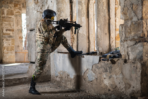 A woman in an army uniform shoots a firearm in an abandoned building. 
