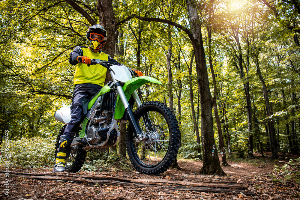 Dirt bike rider enjoying off road ride through the forest and rough terrain.