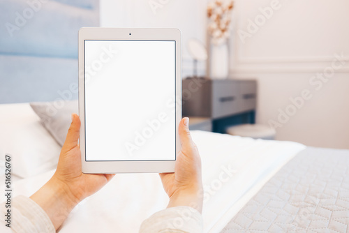 Mockup image of woman's hand holding white tablet pc with blank white screen at home