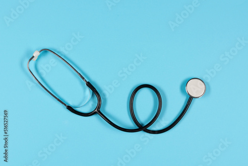 Black stethoscope, top view on the blue background. Medical equipment, tool for measuring the heart rate, lungs, and abdomen sounds