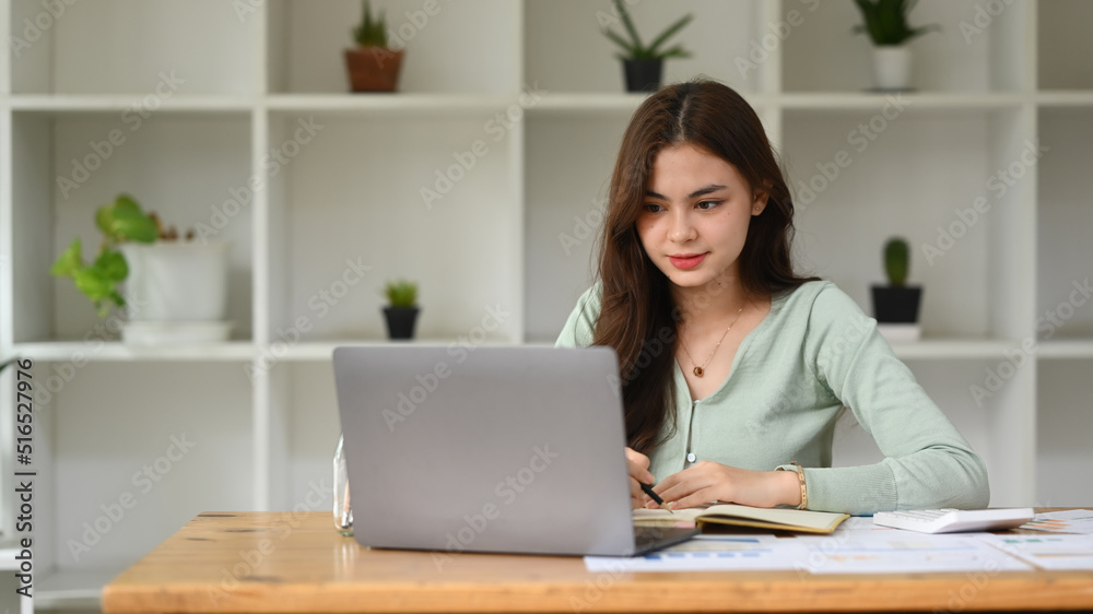 Female economist using laptop and working with statistics graphs at her personal office Female economist using laptop and working with statistics graphs at her personal office