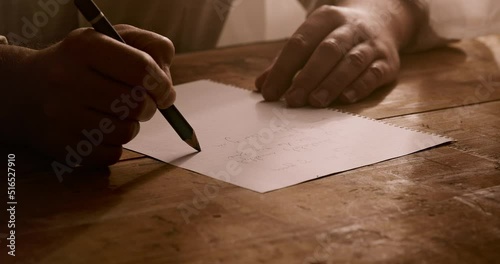 a man writes a letter on a paper on a table. Close up