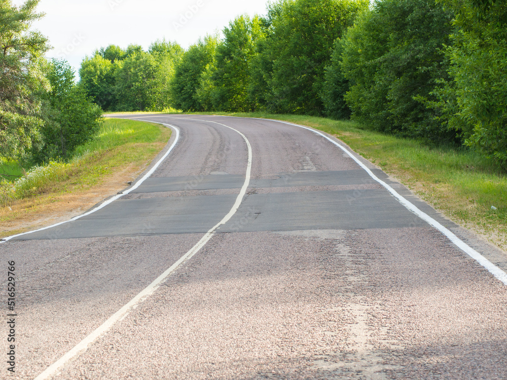 Obraz premium Empty turning rural highway under blue sky on a summer day