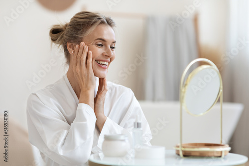 Smiling blonde woman making anti-aging face massage photo