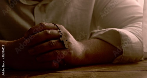 A Christian prays with a cross in his hand. Close up.