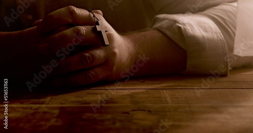 A Christian prays with a cross in his hand. Close up.