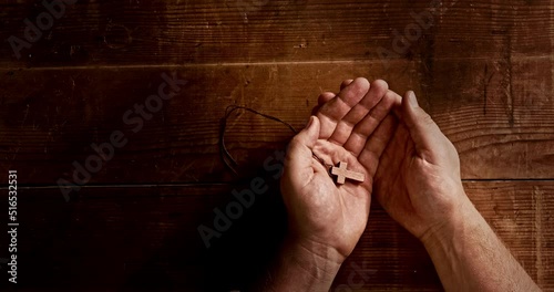 A man holds a cross in his hand and closes his palms.
