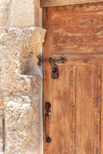 Decorative  massive wooden door with a metal bolt and a metal padlock to a residential building in the Arab Christian village Miilya, in the Galilee, in northern Israel © svarshik