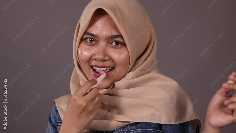 Asian young woman showing skincare products on gray background. Asian young woman showing skincare products on gray background.