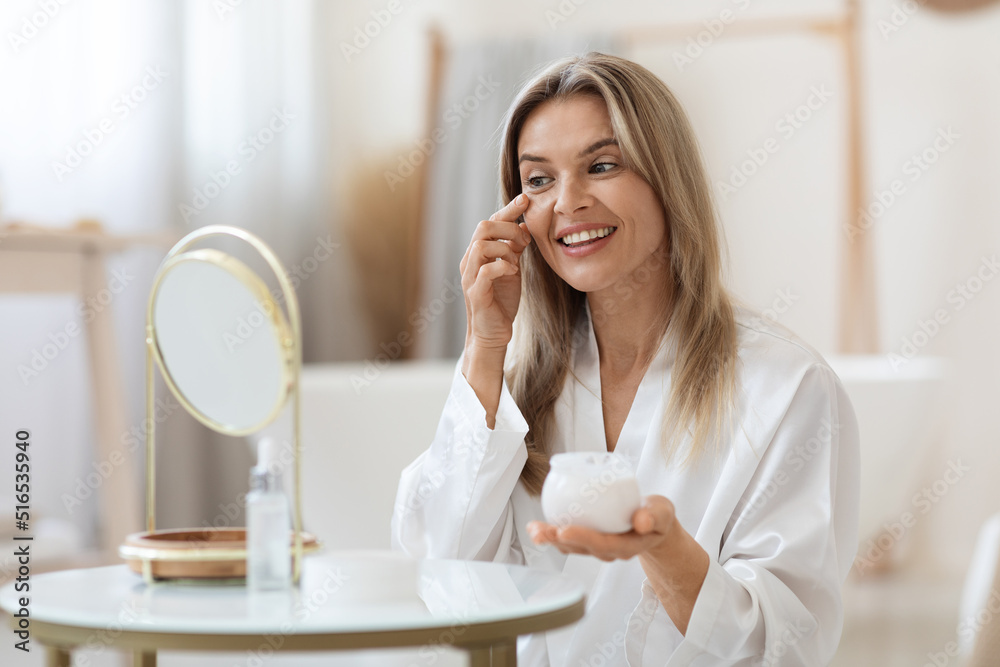 Cheerful beautiful adult lady applying eye cream Cheerful beautiful adult lady applying eye cream
