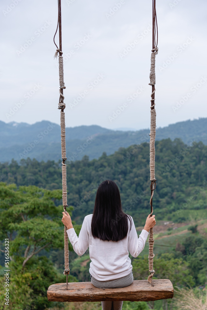 Woman playing swing among range of mountain and valley