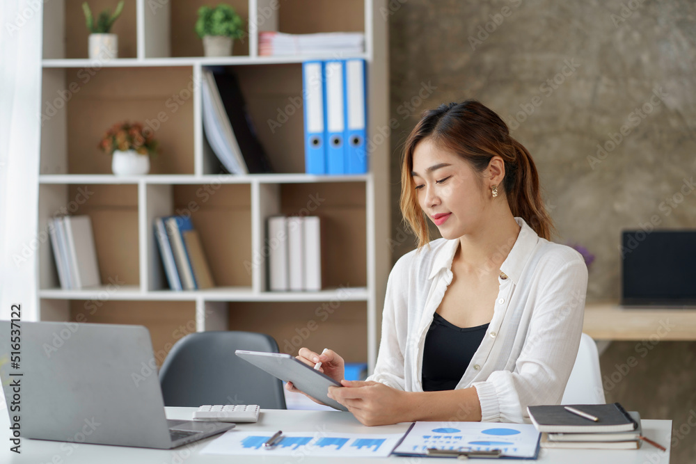 Pretty Asian business woman sitting happily working with laptop computer in the office. Pretty Asian business woman sitting happily working with laptop computer in the office.