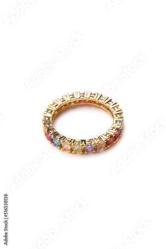 Close-up shot of a gold tone ring embellished with sparkling colored crystals. The gold sparkling ring is isolated on a white background. Top view.