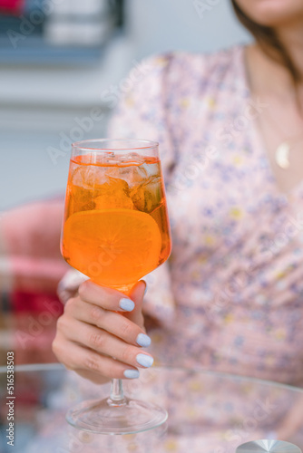 Woman drinking italian aperol cocktail on cafe terrace on sunny day.