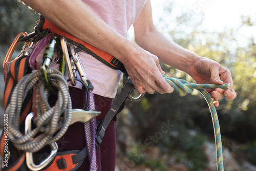 A rock climber prepares equipment for climbing, woman holds a rope, knot © zhukovvvlad
