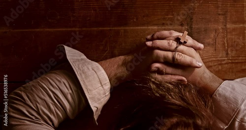 A Christian bows his head in prayer with a cross in his hand. Top shot.