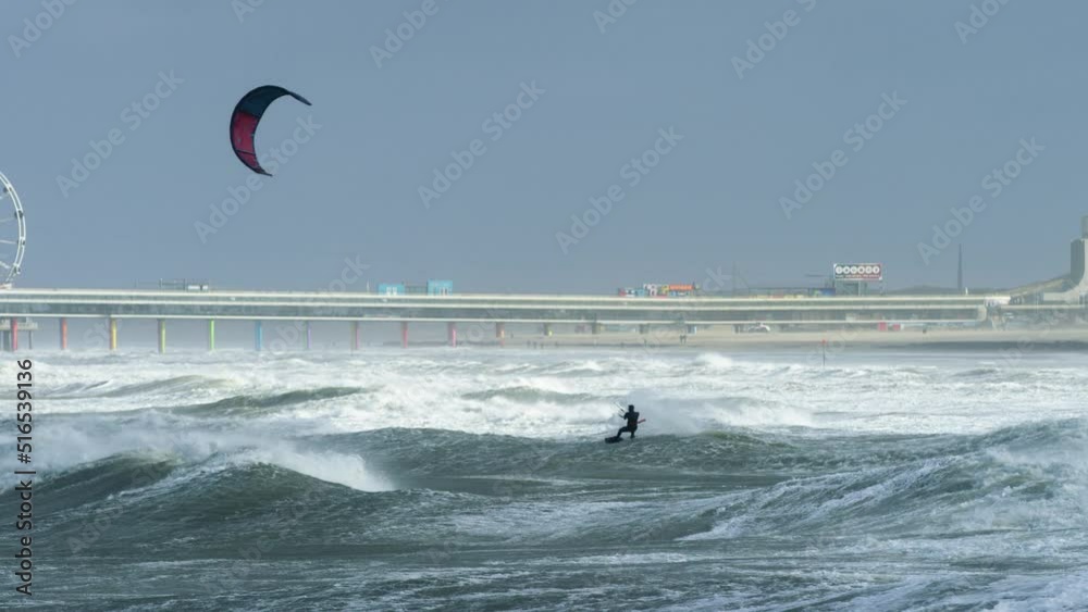 A dynamic footage of a kite surfer surfing under the harsh weather and ...