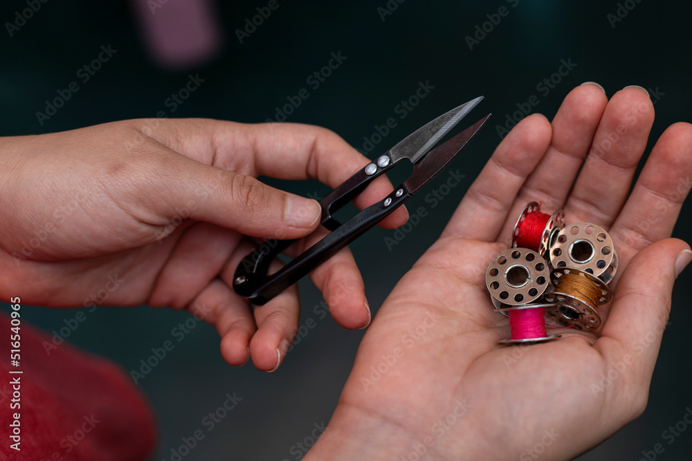 Fototapeta premium Latin American seamstress with scissors and spool of sewing machine thread in hand.