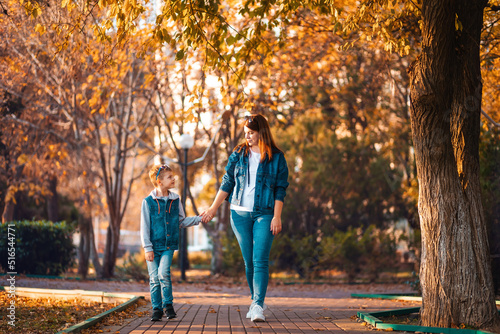Young mother and son holding hands and walking together in the autumn park. The concept of happy family