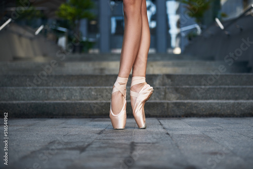 beautiful legs of a ballet dancer in pointe balancing. Pointe shoes close up, Ballerina. Street photo. grey stairs background