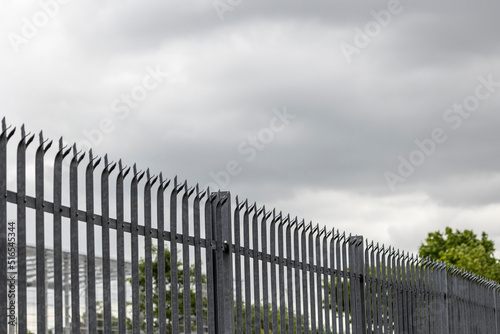Galvanized steel palisade fence on the border of a property photo