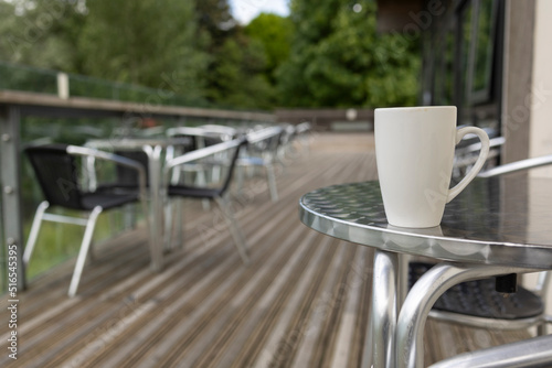 isolated plain white coffee cup on a aluminium cafe table selective focus