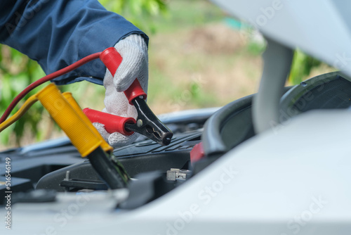 Car service, repair, maintenance concept. Close up of hands electrician repairs car, tester and engine oil and nippers.call a technician broken car emergency on the way