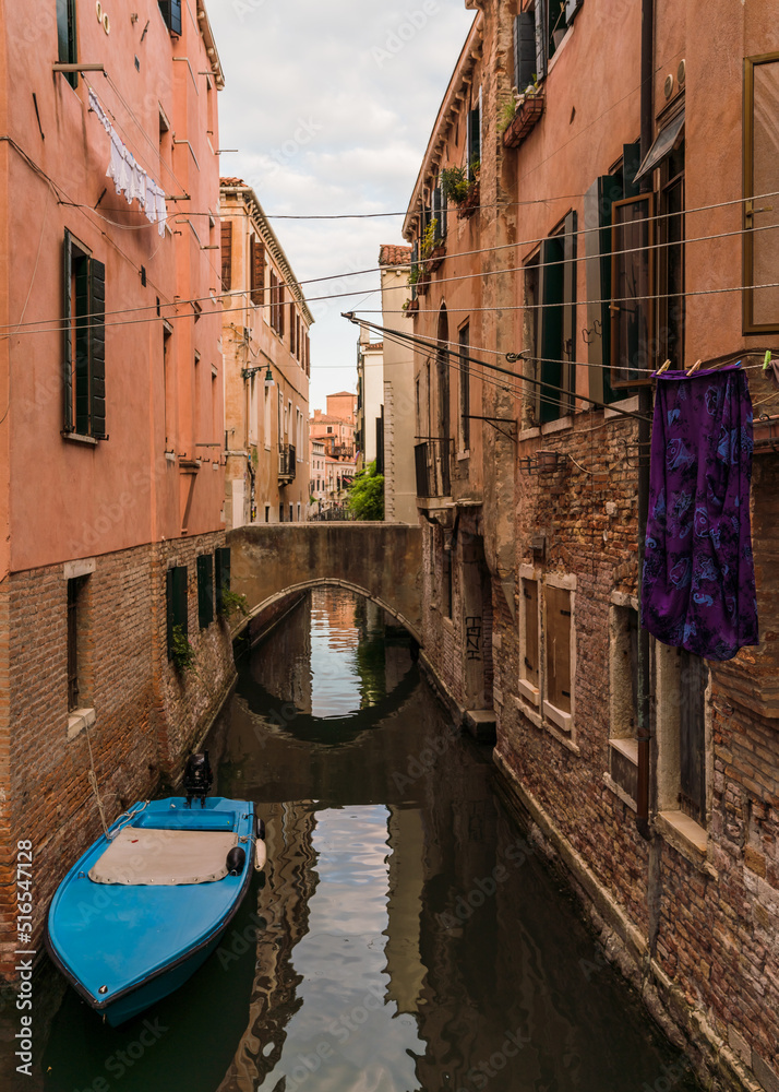 View of a charming canal with boats docked, in Venice Italy and traditional Venetian gothic architecture 