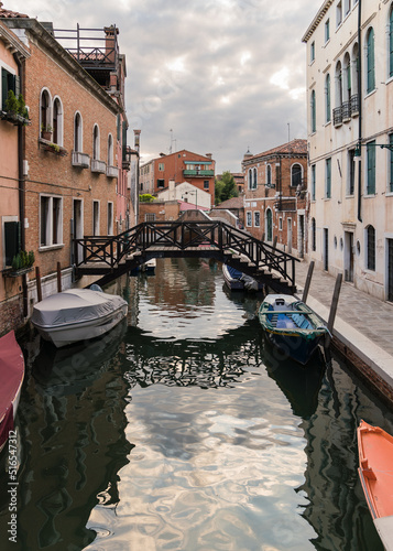 View of a charming canal with boats docked  in Venice Italy and traditional Venetian gothic architecture 