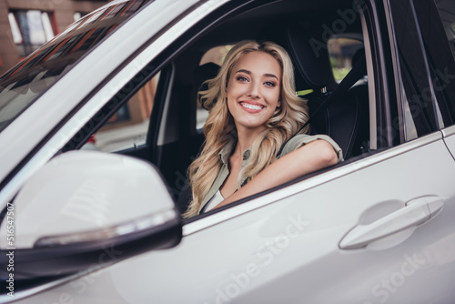 Photo of cheerful pretty lady sitting car driver seat look through window toothy smile