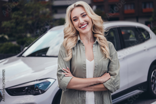 Portrait of attractive cheerful wavy haired girl taking modern car for rent spending day holiday weekend outside © deagreez