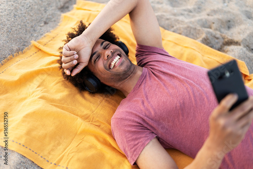 Happy smling man sunbathing on beach towel. Handsome man relaxing at the beach photo